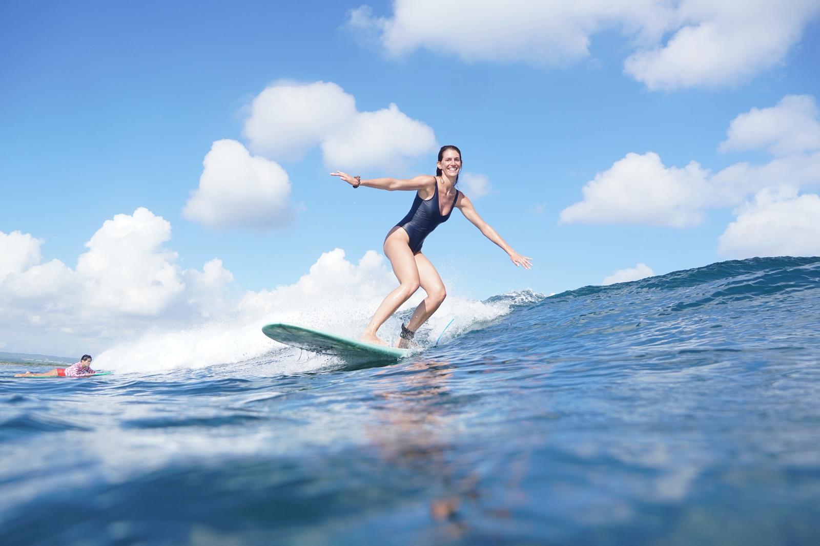 Smiling surfer cruising a longboard on a clean wave at Kuta Reef, Bali